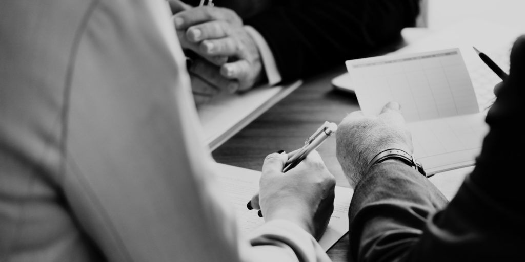 people looking at paper with a pen in hand