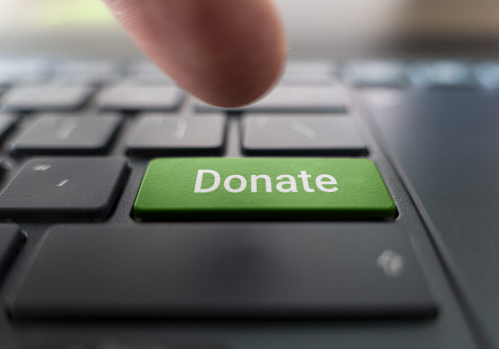 Red donate button on the keyboard close-up. blurred in motion background.