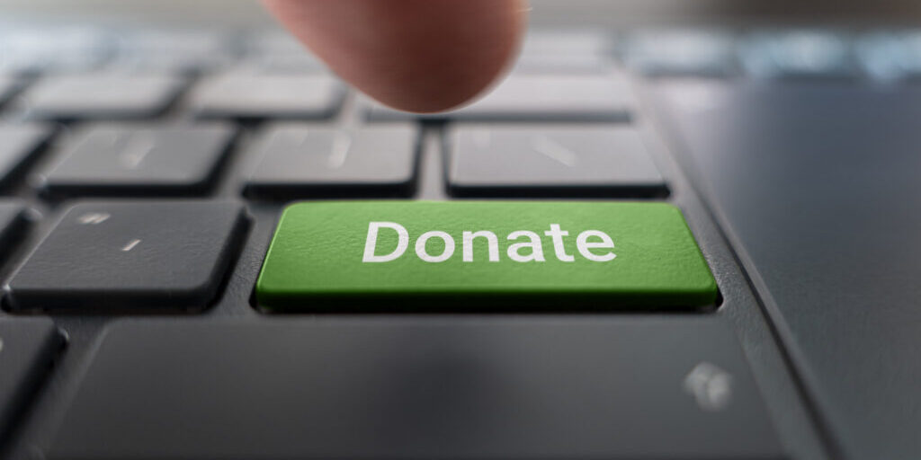 Red donate button on the keyboard close-up. blurred in motion background.