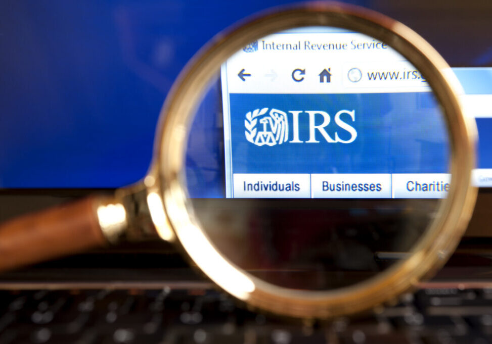 "Izmir, Turkey - June 12, 2012: Close up to IRS( Internal Revenue Service) website through a magnifying glass on the laptop. IRS is a United States government agency tasked with collecting yearly state and income tax from working residents and businesses."