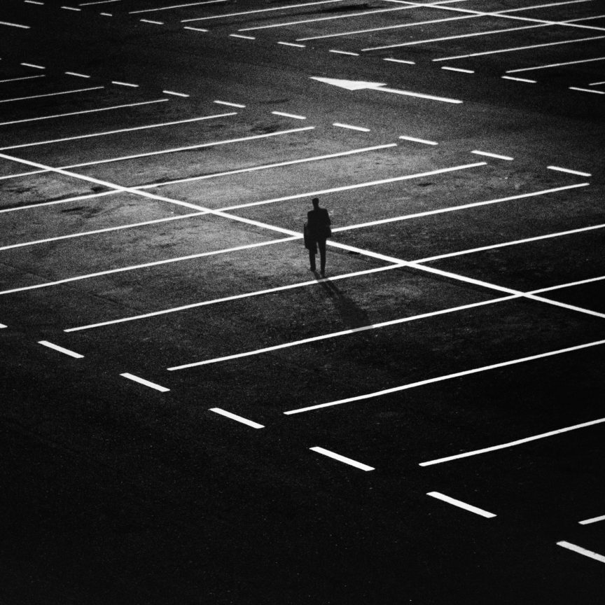 man-standing-on-parking-lot-163772 one person walking alone