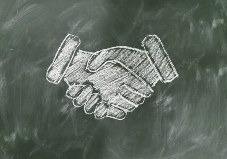 shaking hands drawn in white chalk on green board.